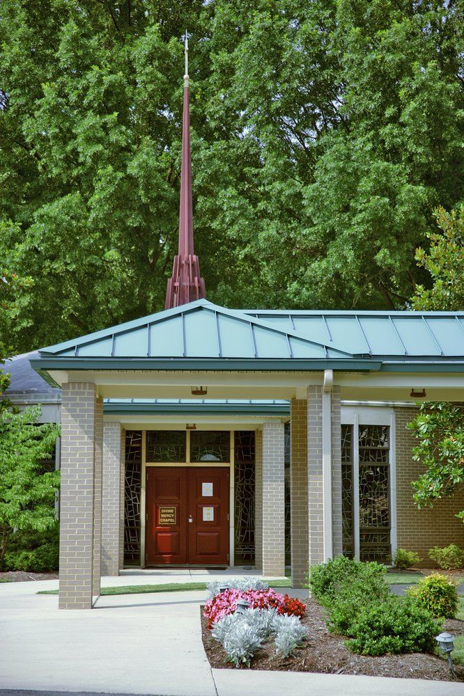 A small church building with a steeple surrounded by trees.