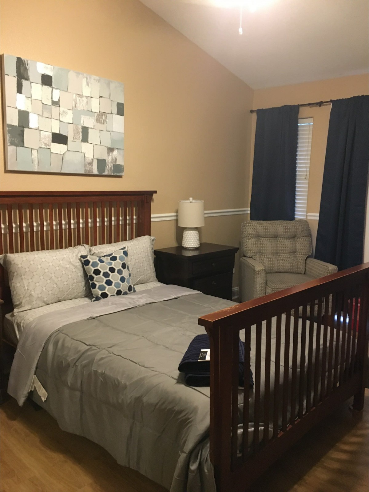 A cozy bedroom featuring a comfy bed, crib, and stylish decor.