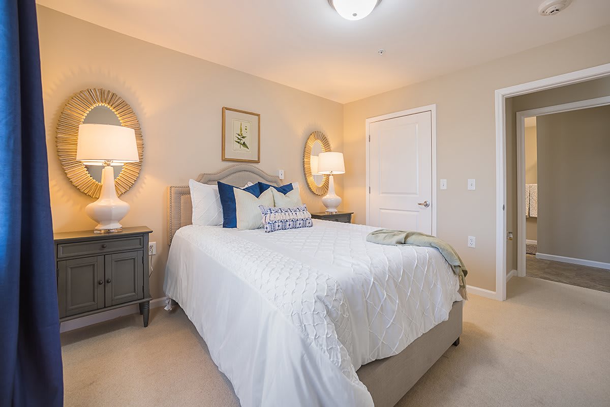 A cozy and well-decorated bedroom featuring a comfortable bed, two lamps on side tables, and decorative mirrors.