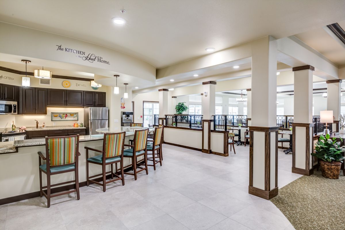 A modern dining area with tables and chairs, featuring an open kitchen design.