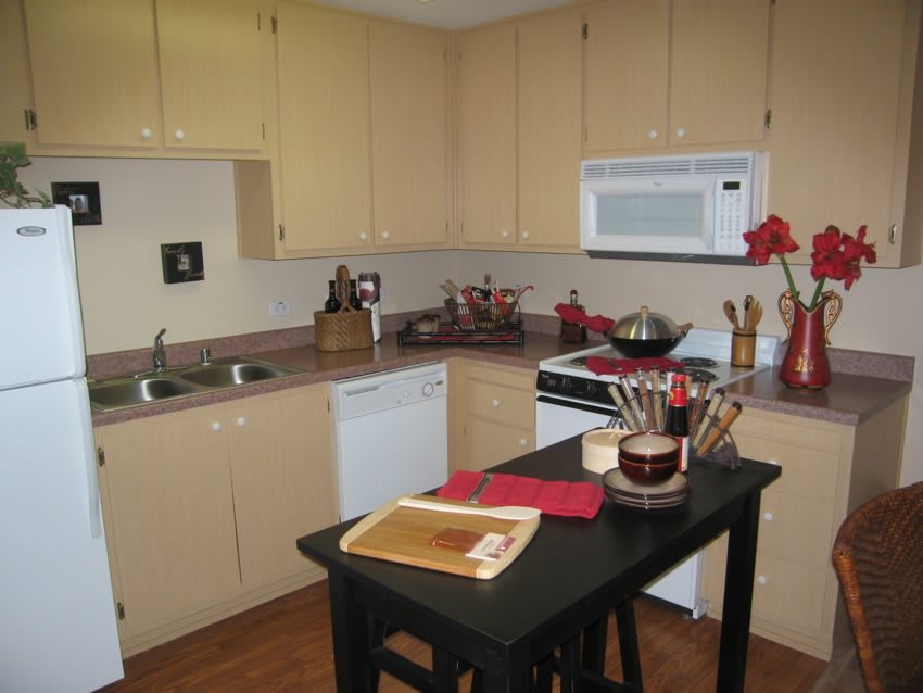 A cozy kitchen setup with light-colored cabinets, dark countertop island, and modern appliances.