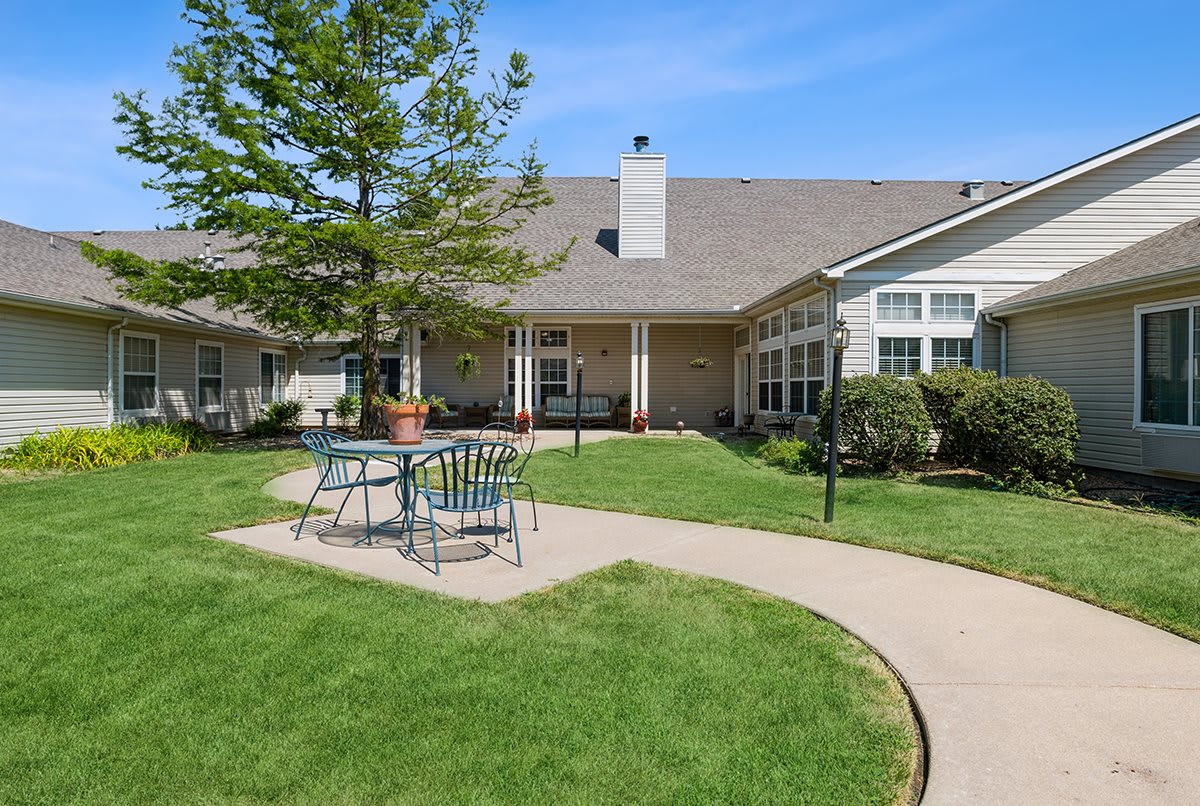 A sunny backyard with a well-maintained lawn and patio furniture.