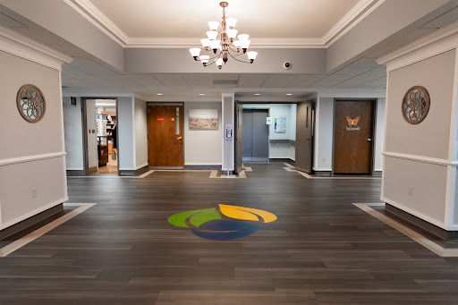 A spacious and modern lobby featuring a stylish chandelier and elegant wooden flooring.