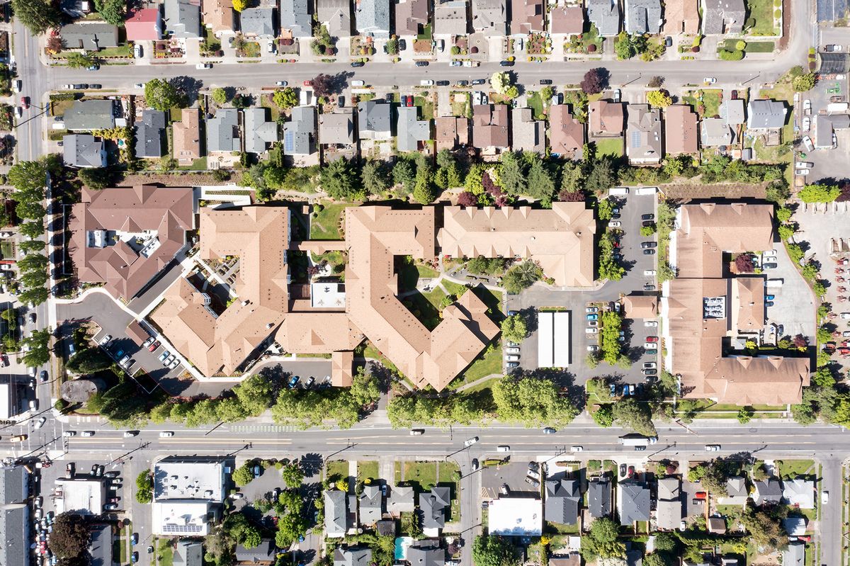 Aerial view of a residential neighborhood with multiple buildings and streets lined with trees.