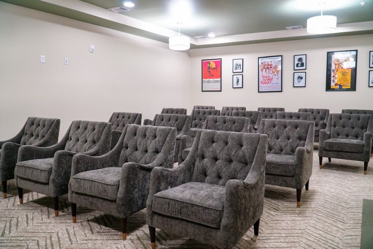 A small theater room with plush seating and movie posters on the wall.