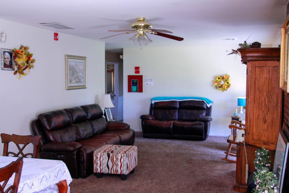 A cozy living room with sofas, a ceiling fan, and home decor.
