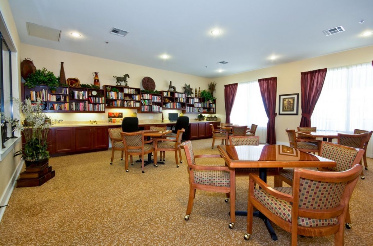 A well-lit study room with tables, chairs, and bookshelves filled with books and decor.