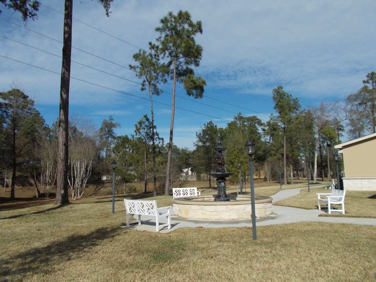 A serene park setting with a central fountain, surrounded by trees and benches.