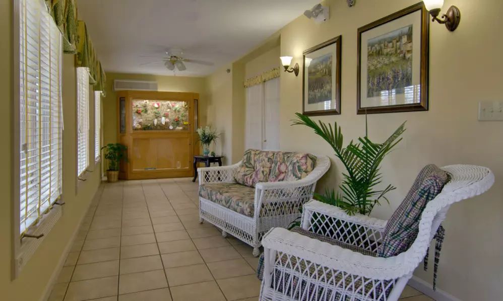 A cozy lobby area with wicker furniture, plants, and artwork on the walls.