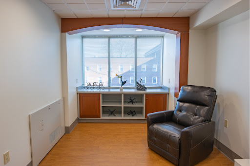 A cozy corner of a room featuring a comfortable chair and a window with natural light.