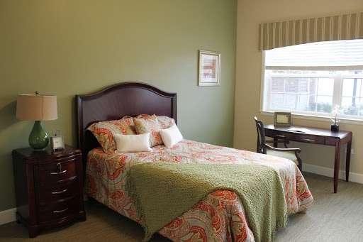 A cozy bedroom featuring a floral patterned bedspread and a desk by the window.