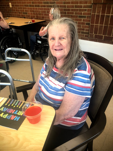 An elderly woman enjoying a cheerful moment in a social setting.