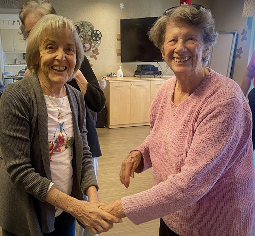 Two women sharing a joyful moment with a handshake.