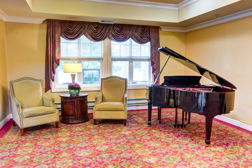 A cozy living room setting with a grand piano and comfortable chairs.