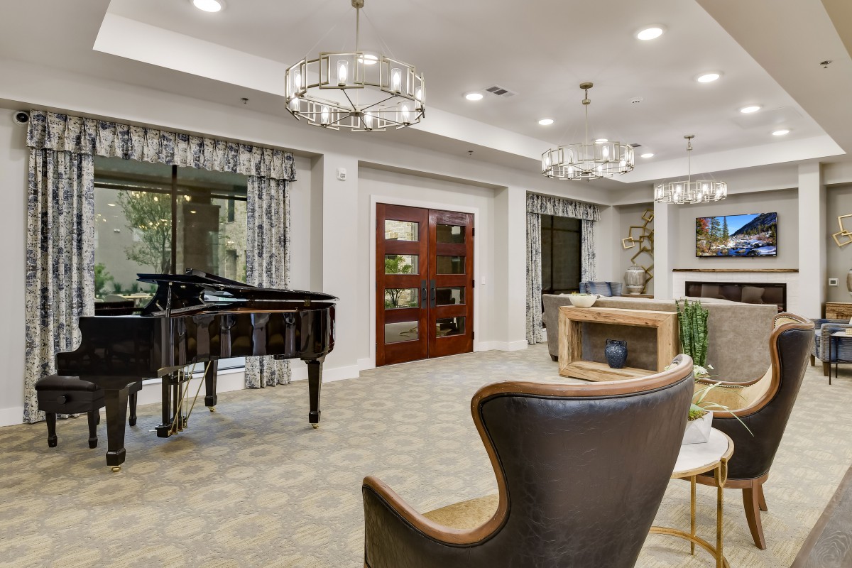 A luxurious living room featuring a grand piano, elegant chandeliers, and modern furnishings.