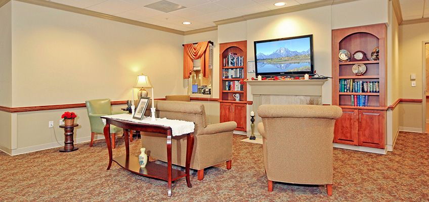 A cozy living room with comfortable seating, a mounted television, and a bookshelf for decor.