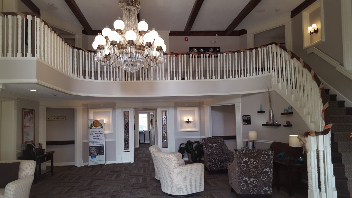 Elegant lobby with a large chandelier, seating area, and balcony.