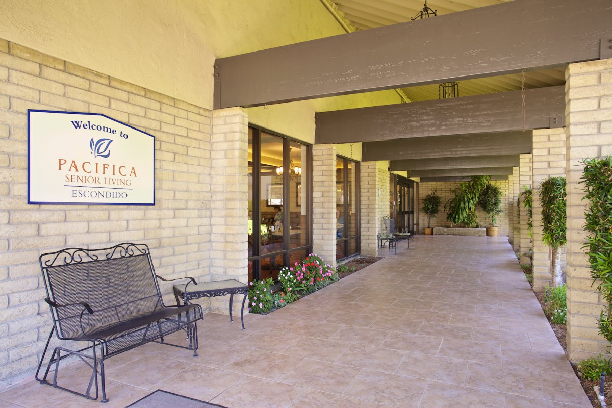 The entryway of a building featuring benches, signage, and a covered walkway.