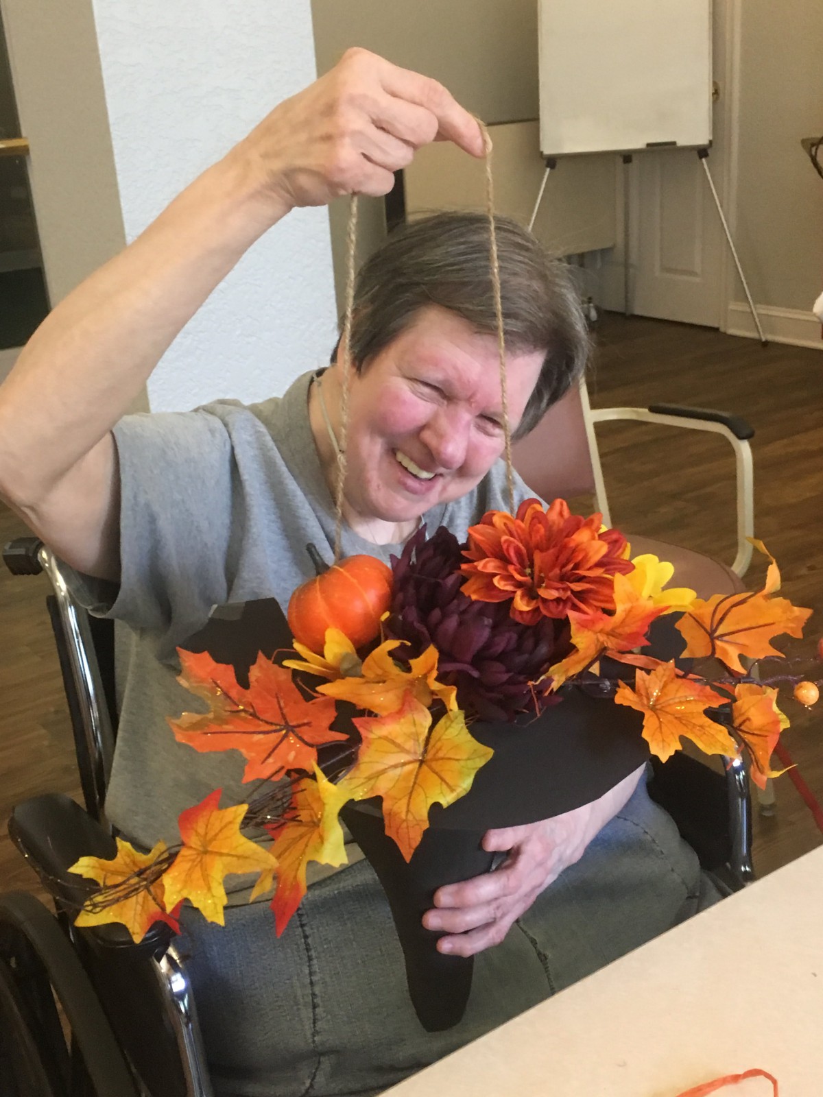 Person enjoying crafting with autumn-themed flowers and leaves.
