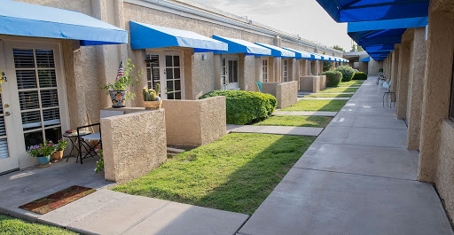 A well-maintained outdoor area featuring buildings with blue awnings and neatly trimmed grass.