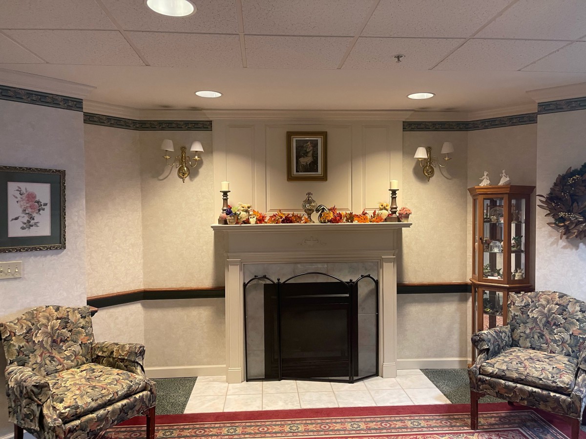 A cozy living room with a decorated fireplace, bookshelves, and comfortable seating.