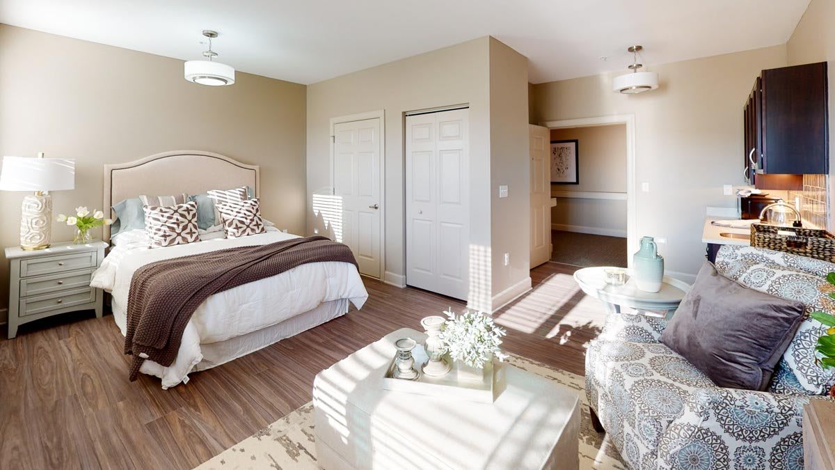 A bright and cozy bedroom featuring a double bed with decorative pillows, neutral color scheme, and ample natural light.