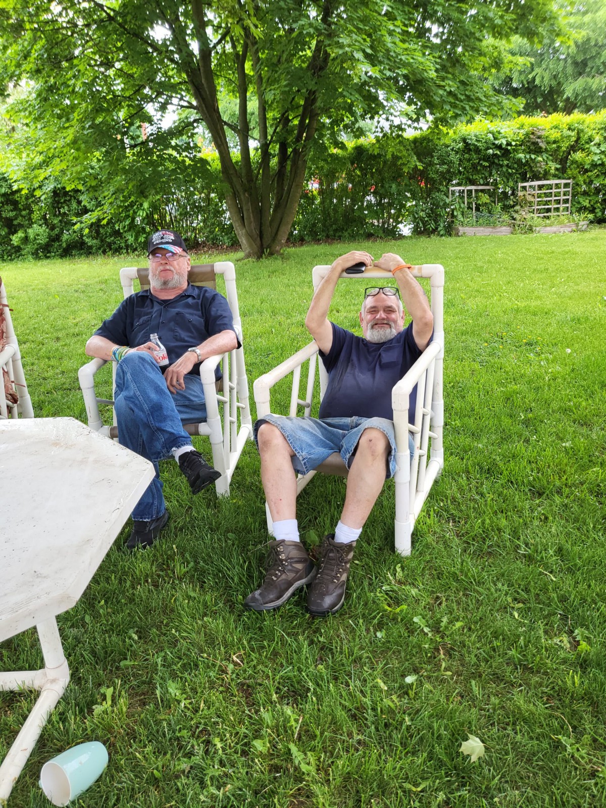 Two people relaxing in chairs on a grassy lawn.