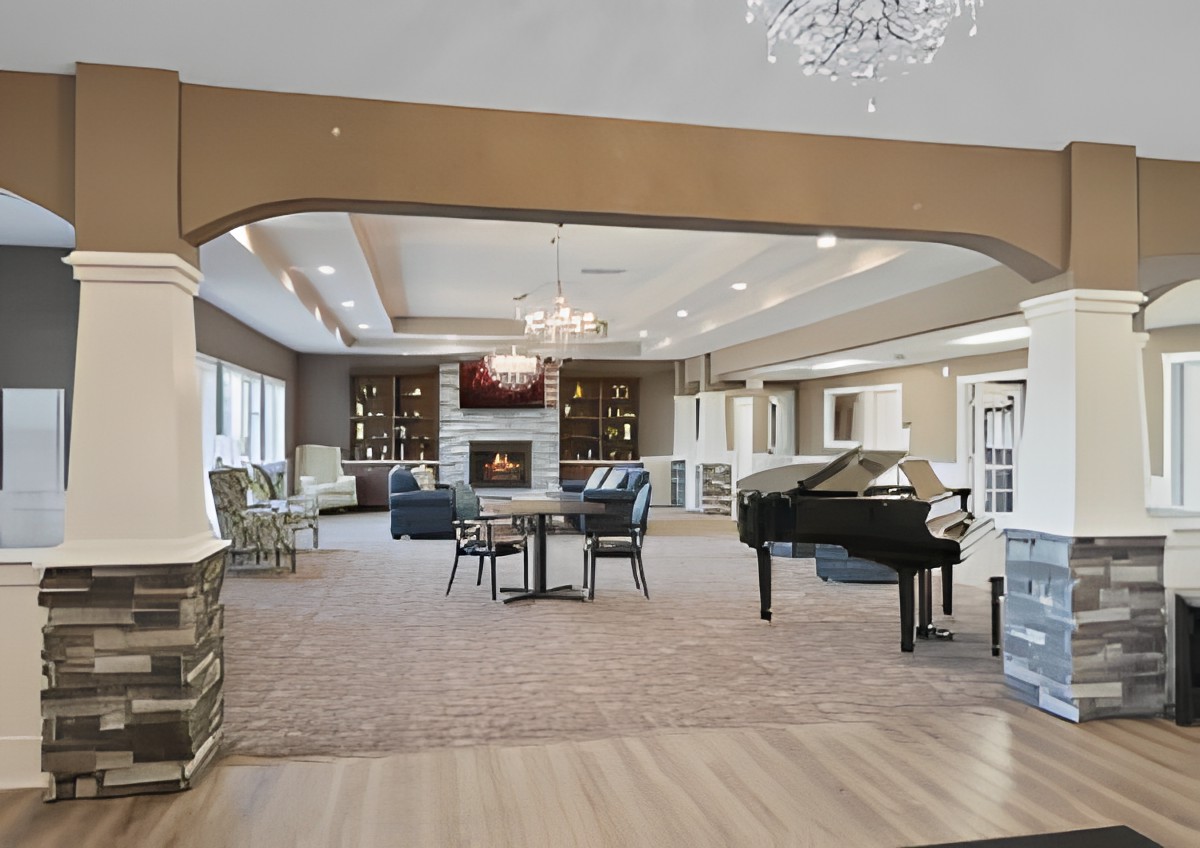 A spacious and elegant living room featuring a grand piano, cozy seating area, fireplace, and bookshelves.