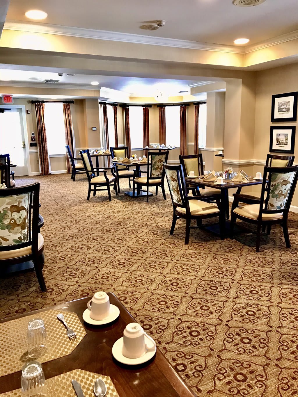 A cozy dining room with neatly arranged tables and chairs, illuminated by warm lighting.