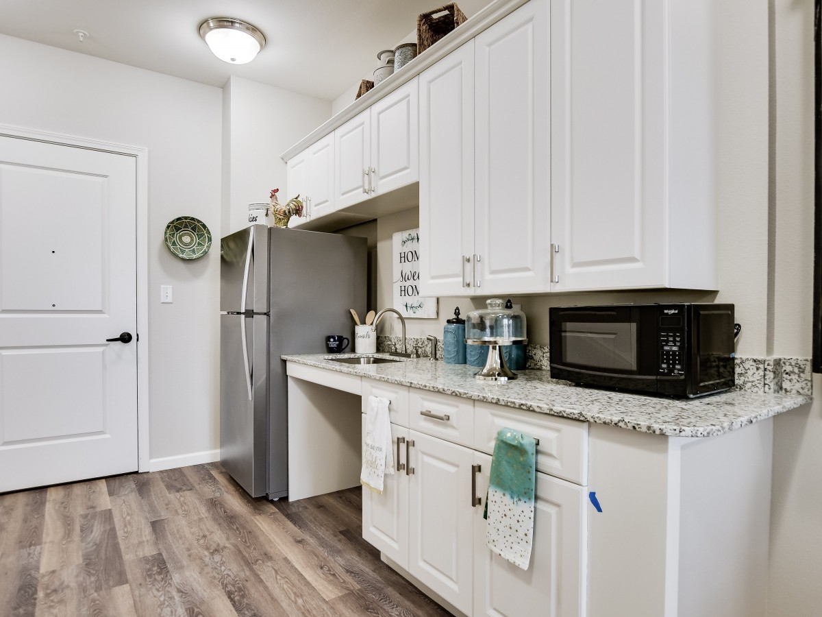 A modern kitchen with white cabinets, a stainless steel refrigerator, and a microwave.