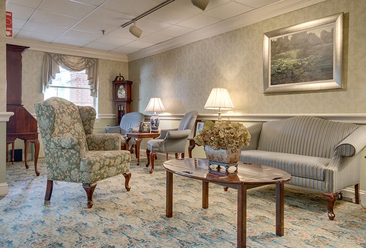 A cozy living room with traditional decor, featuring sofas, armchairs, and warm lighting.