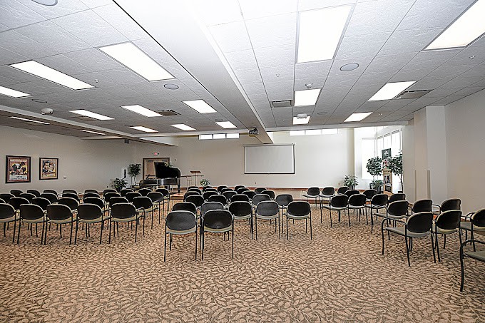 An empty conference room with arranged chairs and a projector screen.