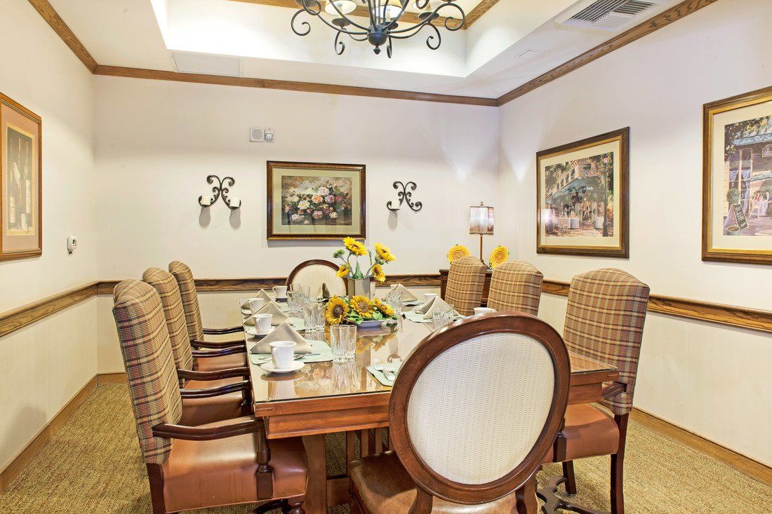 An elegantly decorated dining room with a large table and chairs, featuring sunflowers and framed artwork.