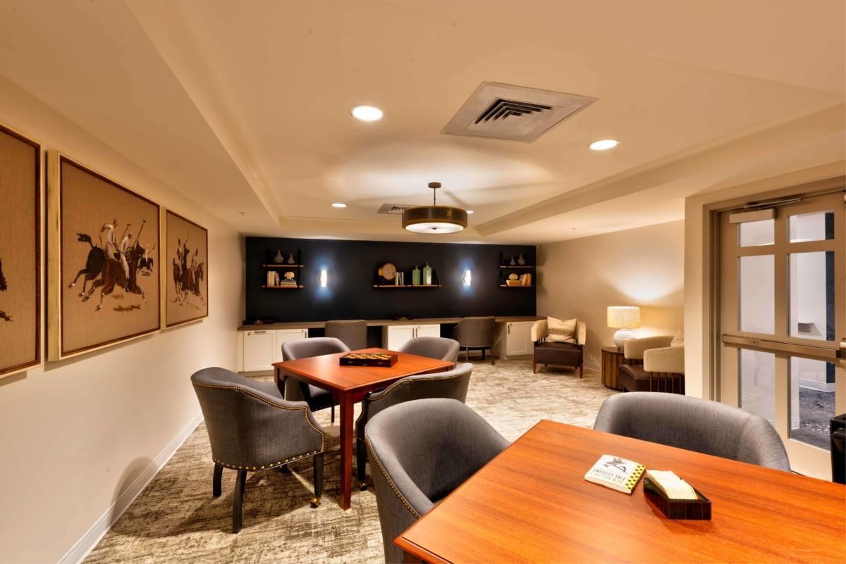 A cozy lounge area featuring modern furniture and warm lighting with tables and upholstered chairs.