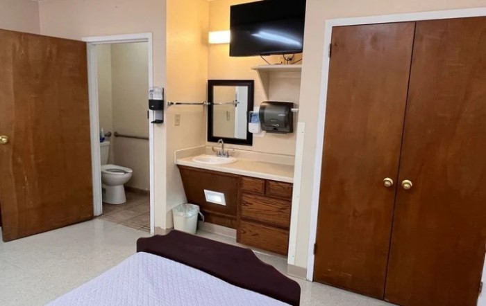 A hotel room featuring a sink, television, and access to a bathroom.