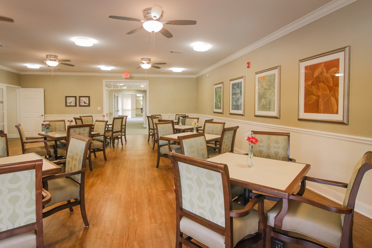 A well-lit dining room with neatly arranged tables, chairs, and decorative wall art.