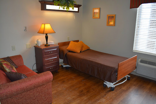 A cozy hospital-style bedroom featuring a single bed, nightstand with a lamp, and a comfortable sofa.
