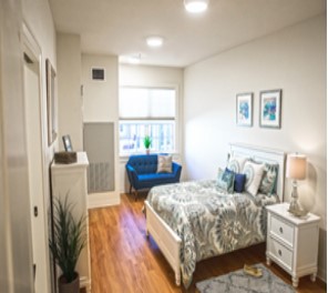 A modern and cozy bedroom with a large bed, stylish decor, and a blue loveseat.