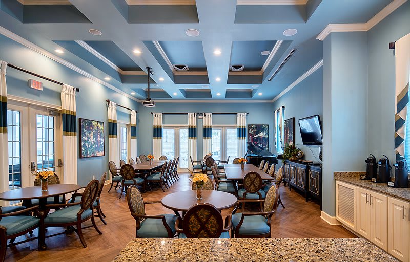 A spacious dining area with elegant furnishings, featuring blue walls and a coffered ceiling.