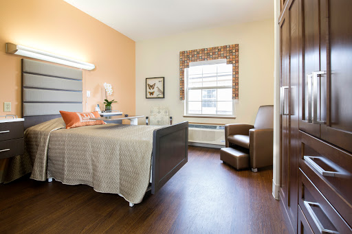 A well-lit hospital room designed for patient comfort, featuring a bed, chair, and window.