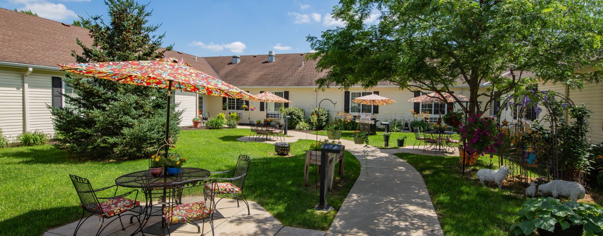 A well-maintained garden with patio seating, umbrellas, and a scenic pathway.