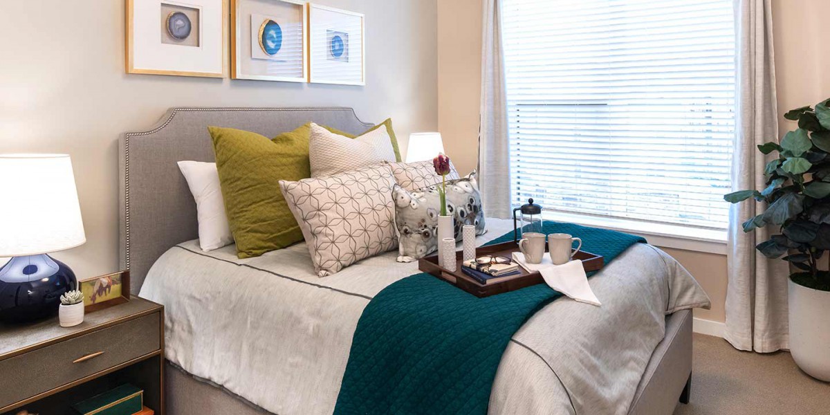 A cozy and well-decorated bedroom with a neatly arranged bed featuring colorful pillows, a teal blanket, and a tray with coffee essentials.