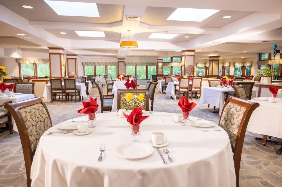 A beautifully set dining area with white tablecloths and red napkins in an elegant restaurant setting.