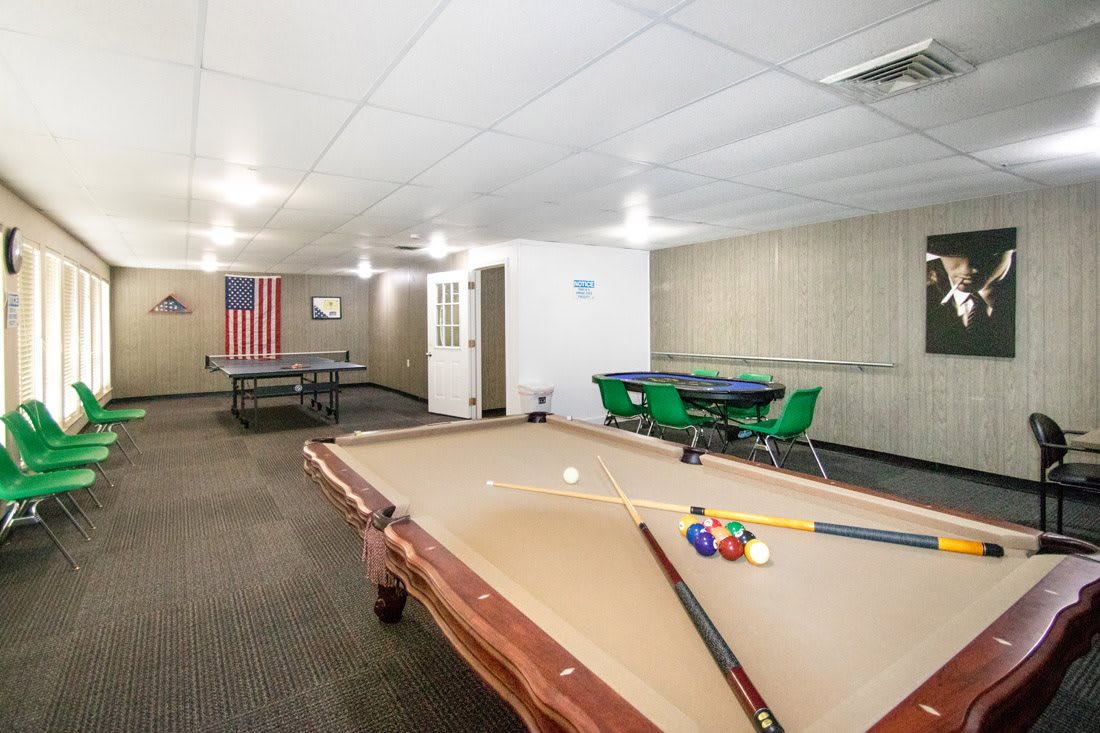 A spacious game room featuring a pool table and a ping pong table with seating areas.