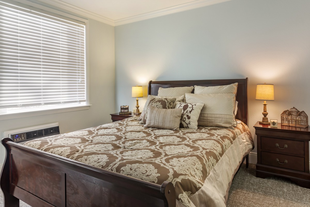 A cozy bedroom with elegant bedding and warm lighting.