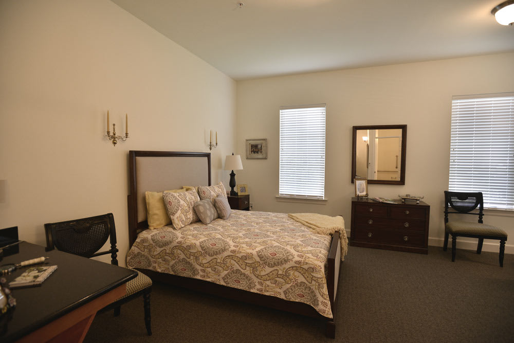 A cozy bedroom with a neatly made bed, decorative pillows, and warm lighting.