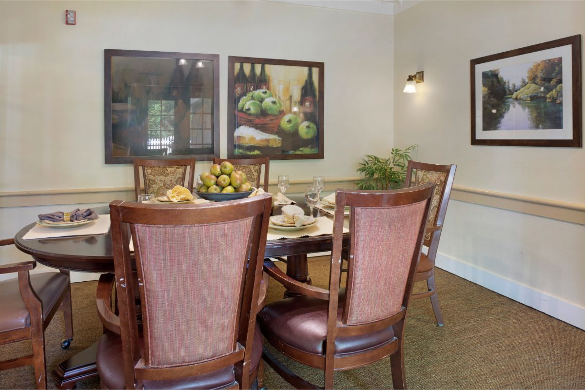 A cozy dining area with a wooden table, surrounded by elegant chairs and decorated with artwork on the walls.