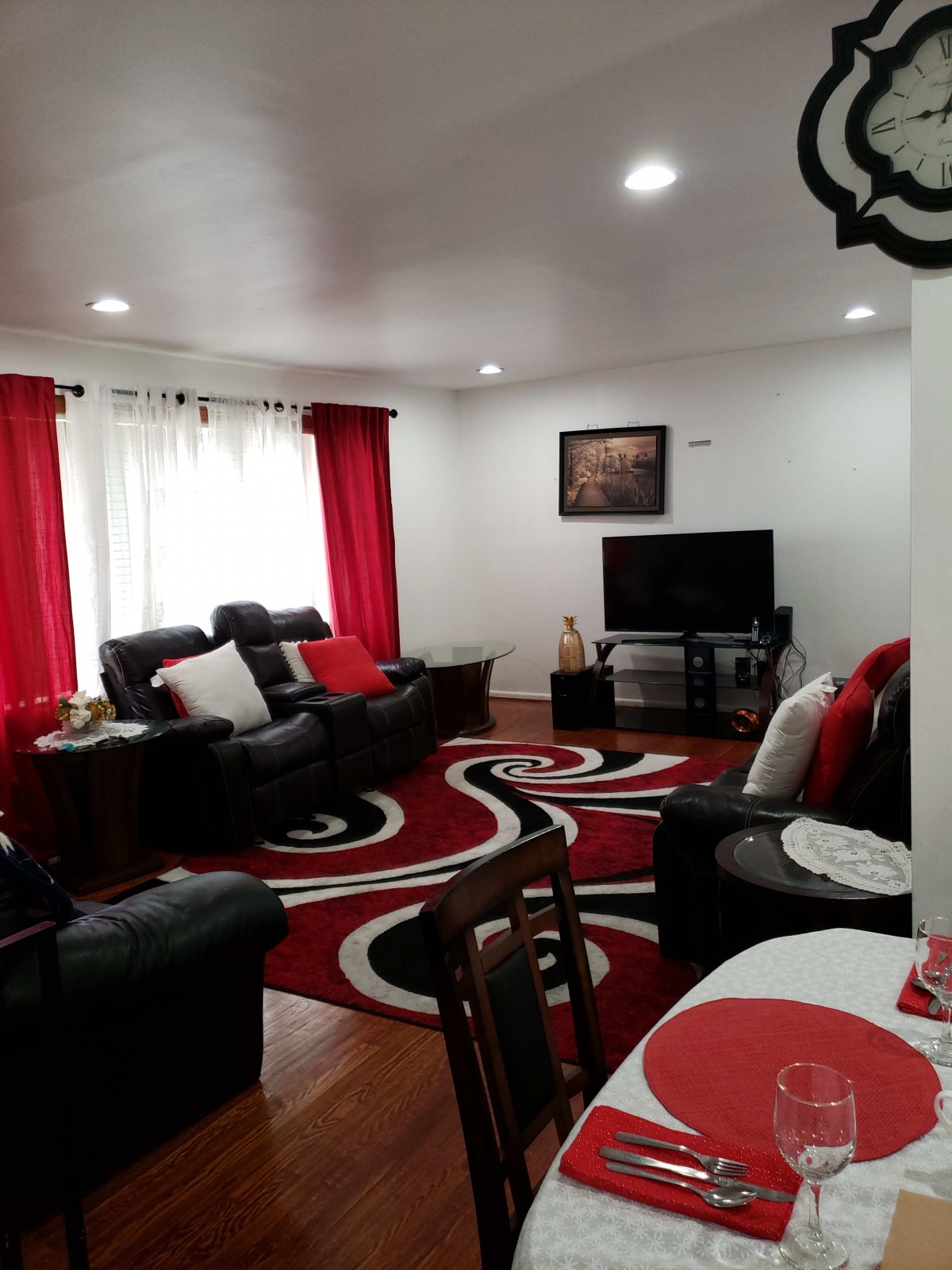 A cozy living room with a modern red and black color scheme, featuring comfortable sofas, a television, and stylish decor.