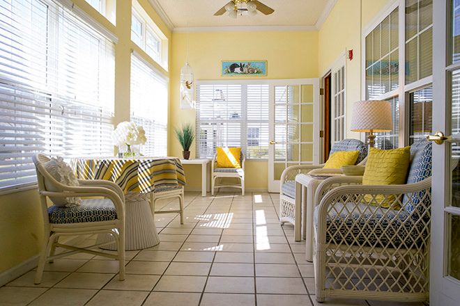 A bright and cozy sunroom with wicker furniture and abundant natural light streaming through large windows.