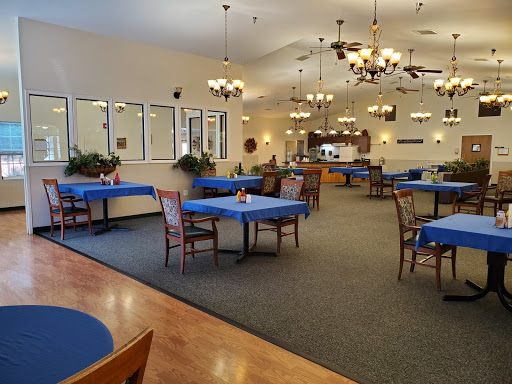 A spacious and elegantly decorated dining area with blue tablecloths and charming chandeliers.
